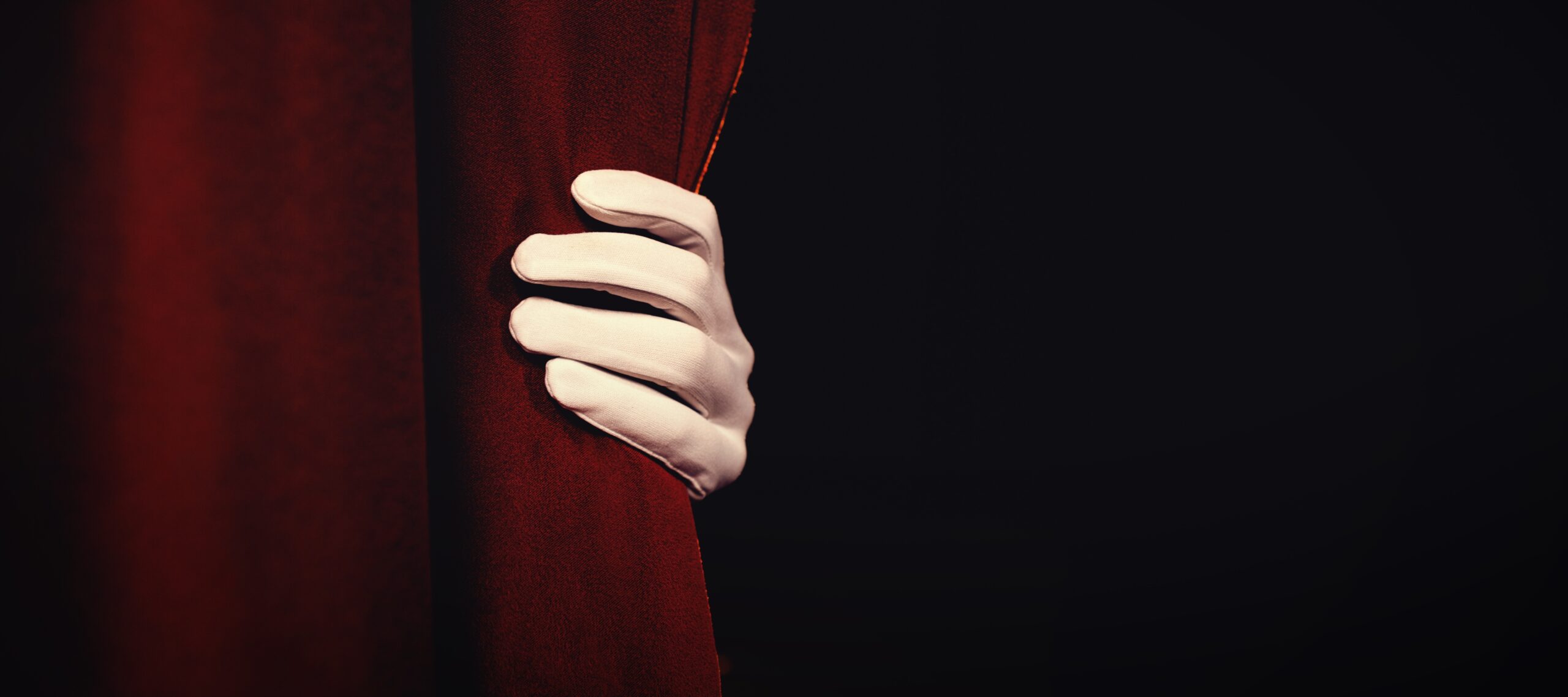 Cropped hand in glove holding curtain